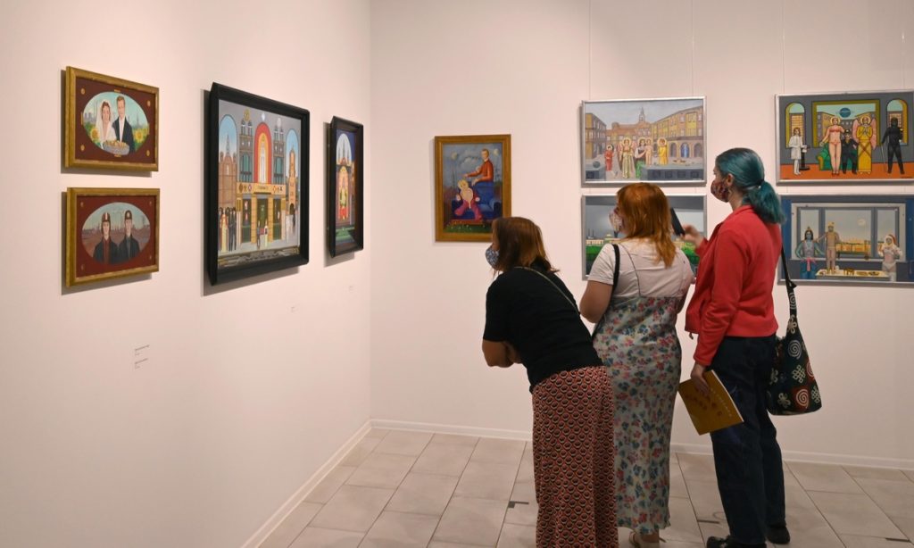 wnętrze galerii, trzy kobiety przyglądają się prezentowanym obrazom