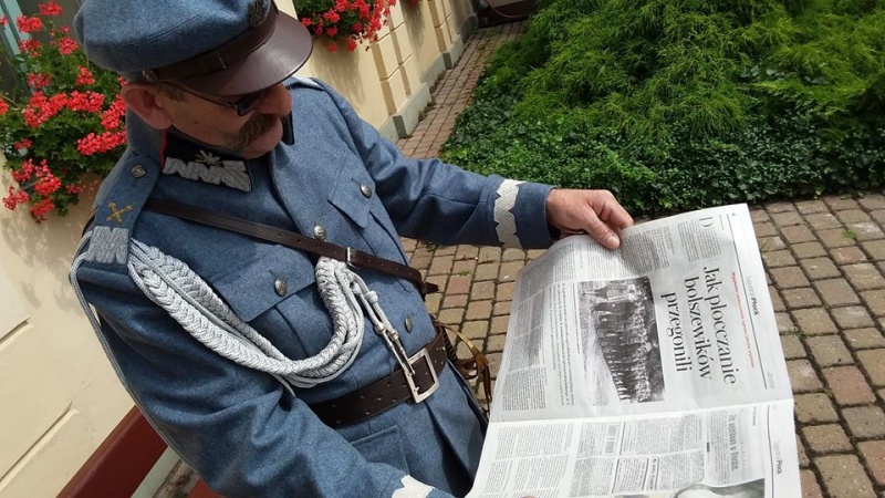 mężczyzna przebrany za marszałka Pilśudskiego siedzi na ławeczce i przegląda gazetę