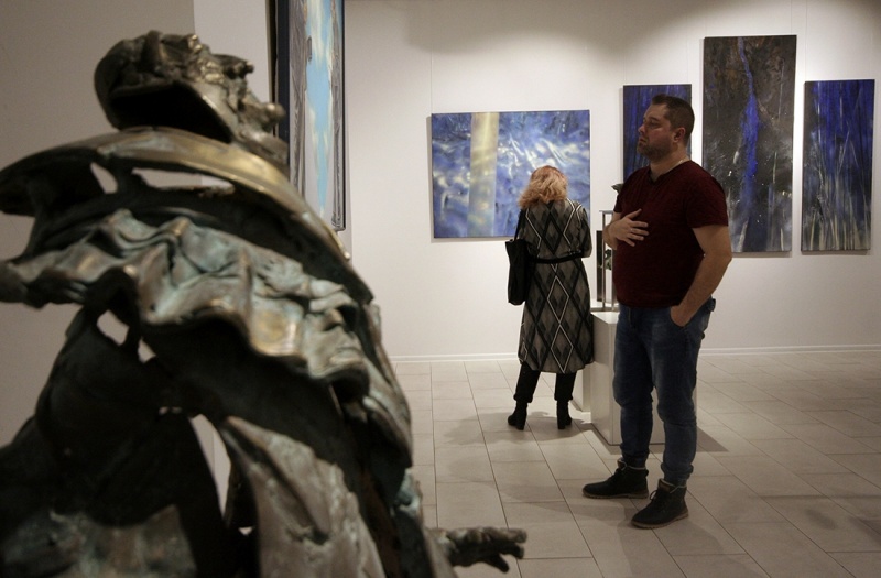 wnętrze galerii, dwie osoby oglądają wystawę, na planie pierwszym rzeźba Ewy Fleszar metalowa postać mężczyzny