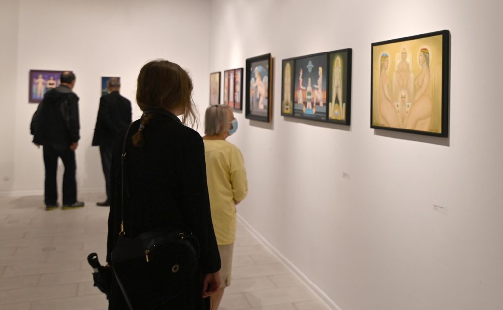 wnętrze galerii, cztery osoby oglądają obrazy Erwina Sówki