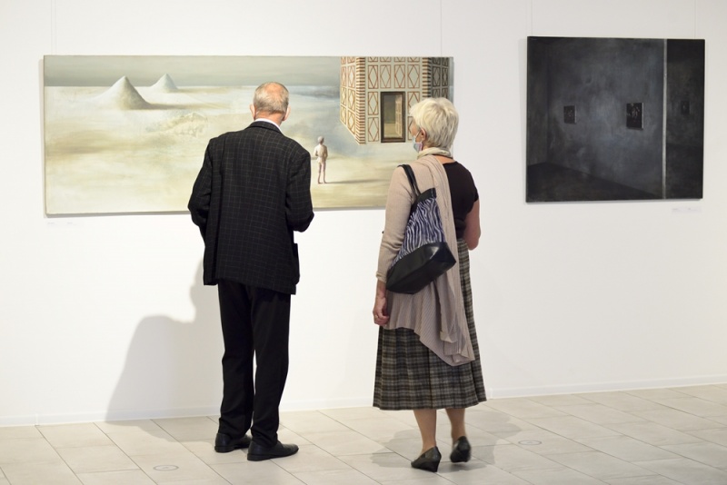 wnętrze galerii, kobieta i mężczyzna oglądają obrazy Łukasza Huculaka