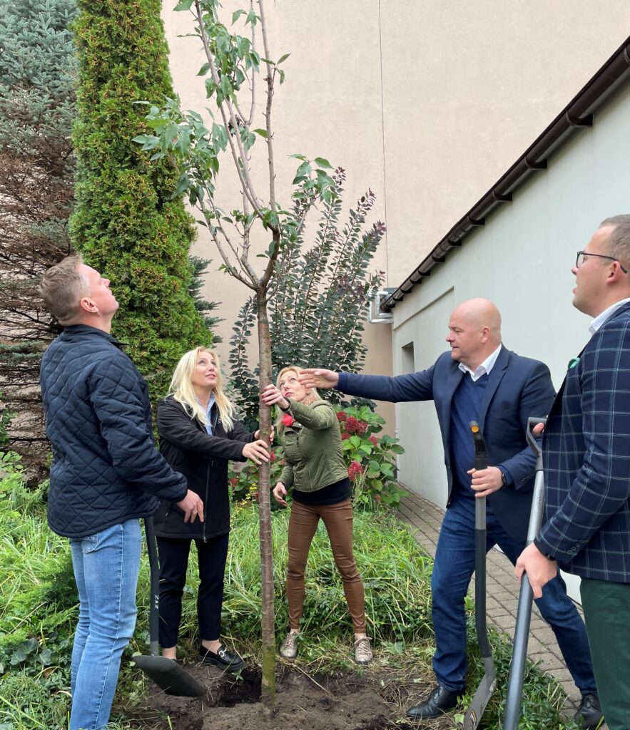 pięć osób sadzie drzewko na świeżym powietrzu, wśród nich jest prezydent Płocka Andrzej Nowakowski i dyrektor PGS Alicja Wasilewska 